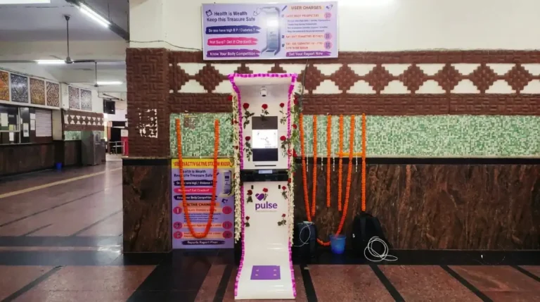 Pulse health kiosk with body composition monitor decorated with flower garlands at a railway station
